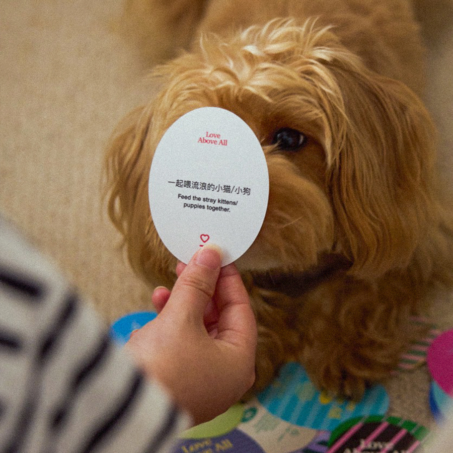 Love Above All card encouraging kindness and compassion, held in front of a dog as part of a meaningful faith-based challenge.