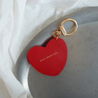 Heart-shaped red keychain engraved with 'Love above all,' a minimalist and faith-inspired accessory, perfect as a unique gift.
