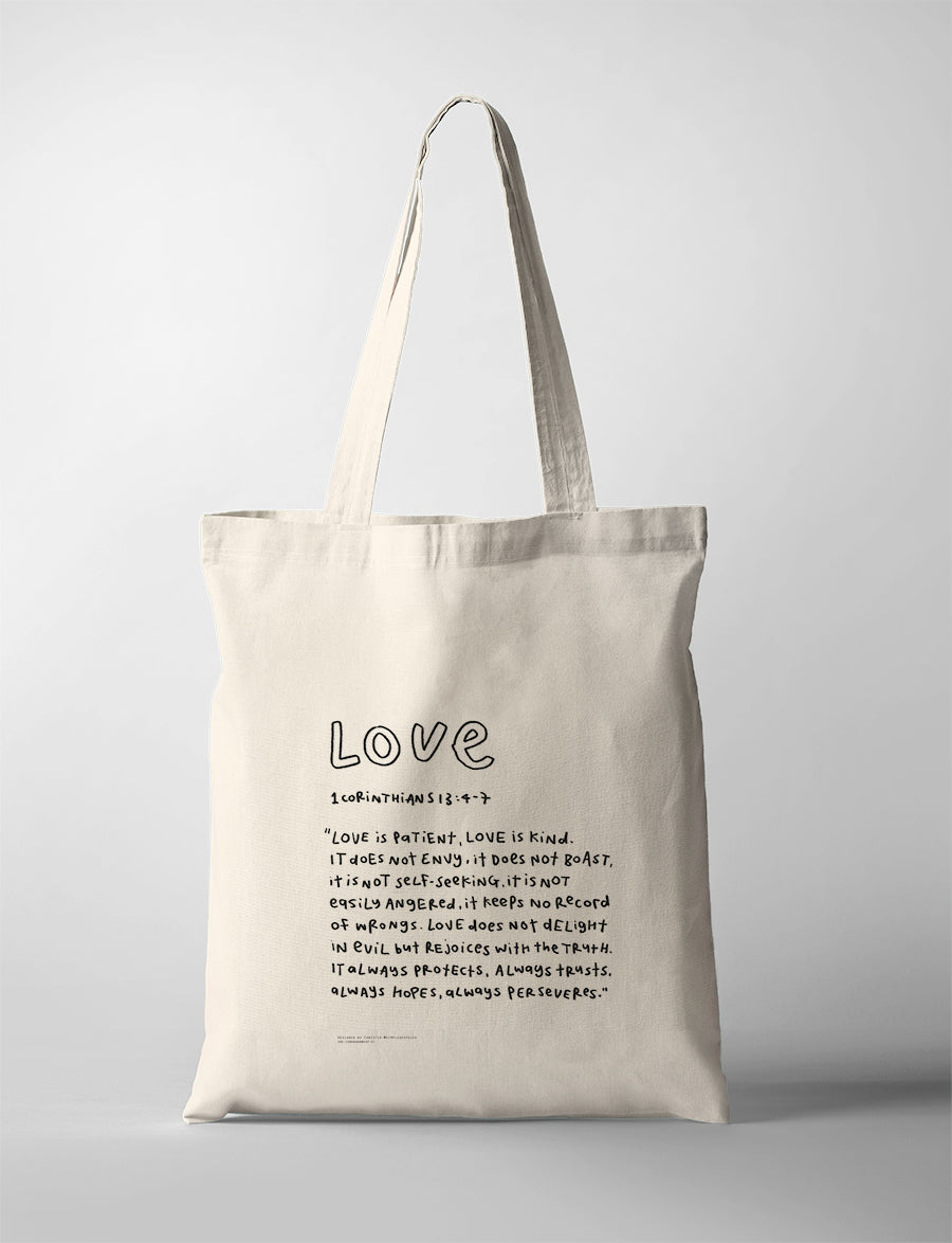 Love Bible verse tote bag featuring 1 Corinthians 13:4-7 in a handwritten typography design on a natural canvas tote.
