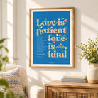 Love Is Patient Love Is Kind blue floral Christian poster framed on a sunlit living room wall
