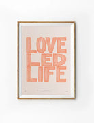 Framed Love Led Life Christian poster with coral striped lettering on a soft blush background