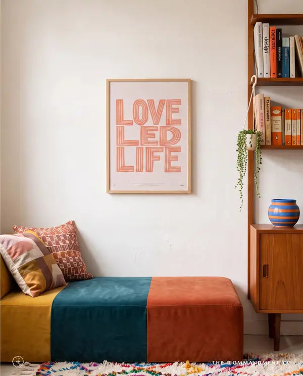 Love Led Life Christian poster displayed above a colourful bench beside a wooden bookshelf