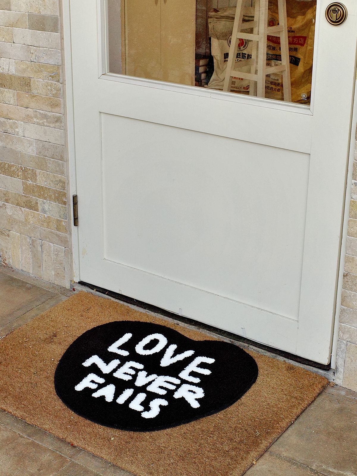 Love Never Fails heart rug placed at an entryway in front of a white door as a faith-inspired welcome mat.