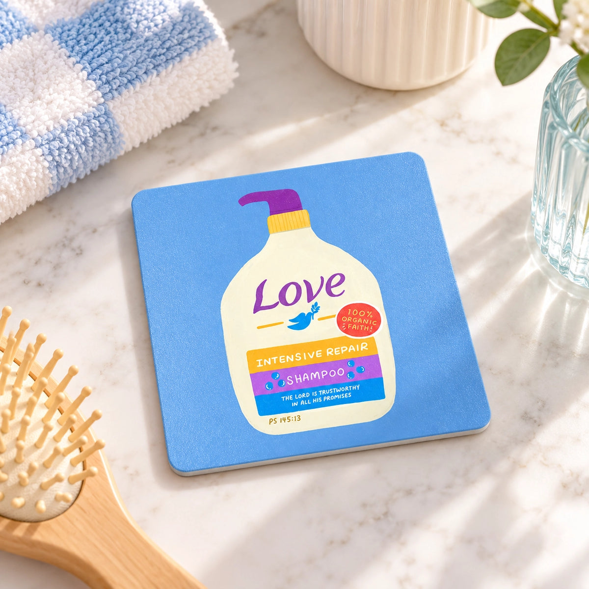 Love Shampoo Christian coaster styled on a bright bathroom counter beside towels and a hairbrush.