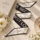 Love Song Christian scarf arranged on a light tabletop beside a journal and flowers
