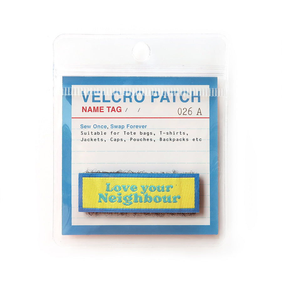 Velcro tag with 'Love your Neighbour' text in blue on a yellow and blue background, a Christian-inspired accessory for clothing and bags.