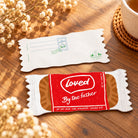 Loved by the Father coffee biscuit-shaped Christian card with red and brown wrapper front and postcard reverse displayed on a wooden table.