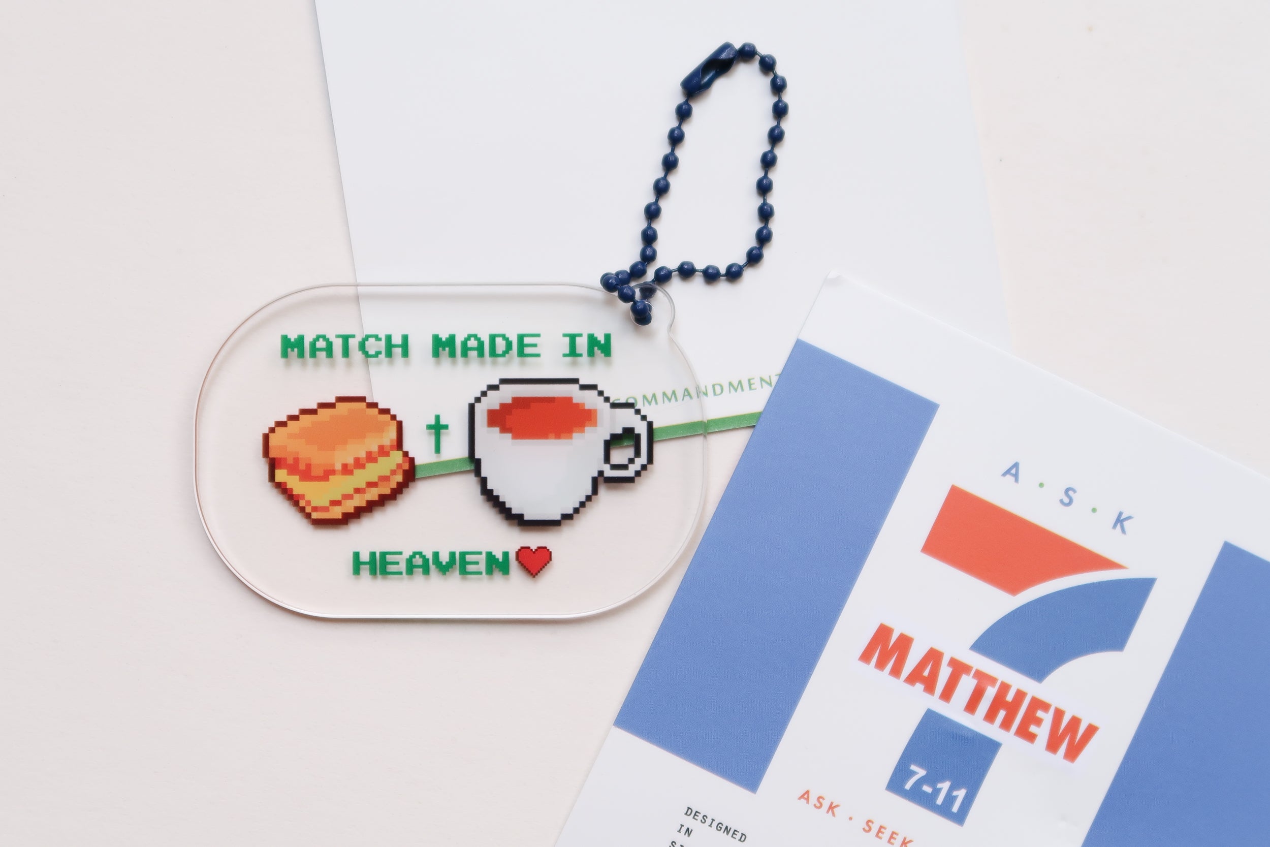  Acrylic keychain with "Match Made in Heaven" design featuring a biscuit and a cup of tea, alongside a Matthew 7:11 card, from The Commandment Co, Singapore.