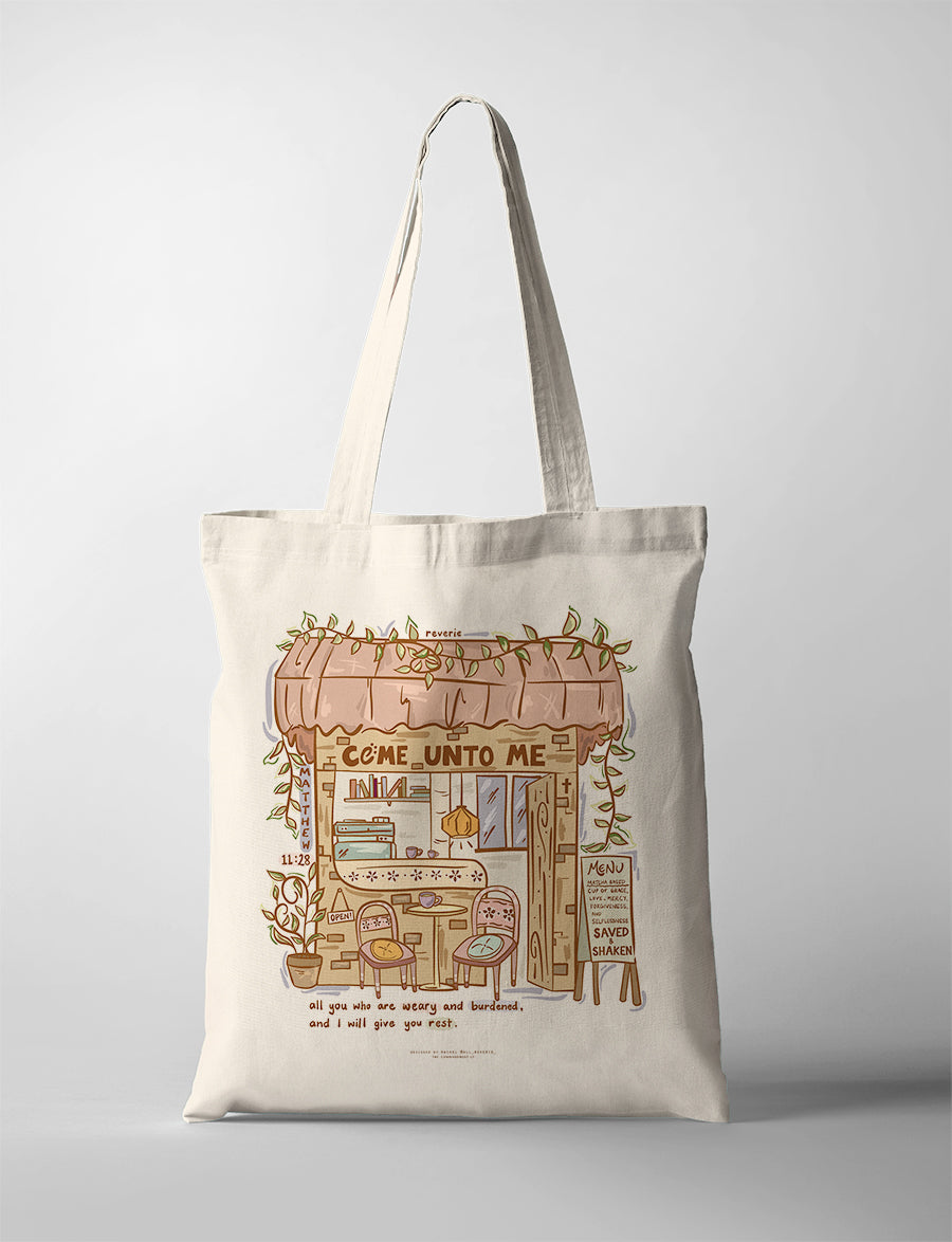 Canvas Christian tote bag featuring cozy café illustration with the verse “Come unto me all who are weary and I will give you rest” from Matthew 11:28