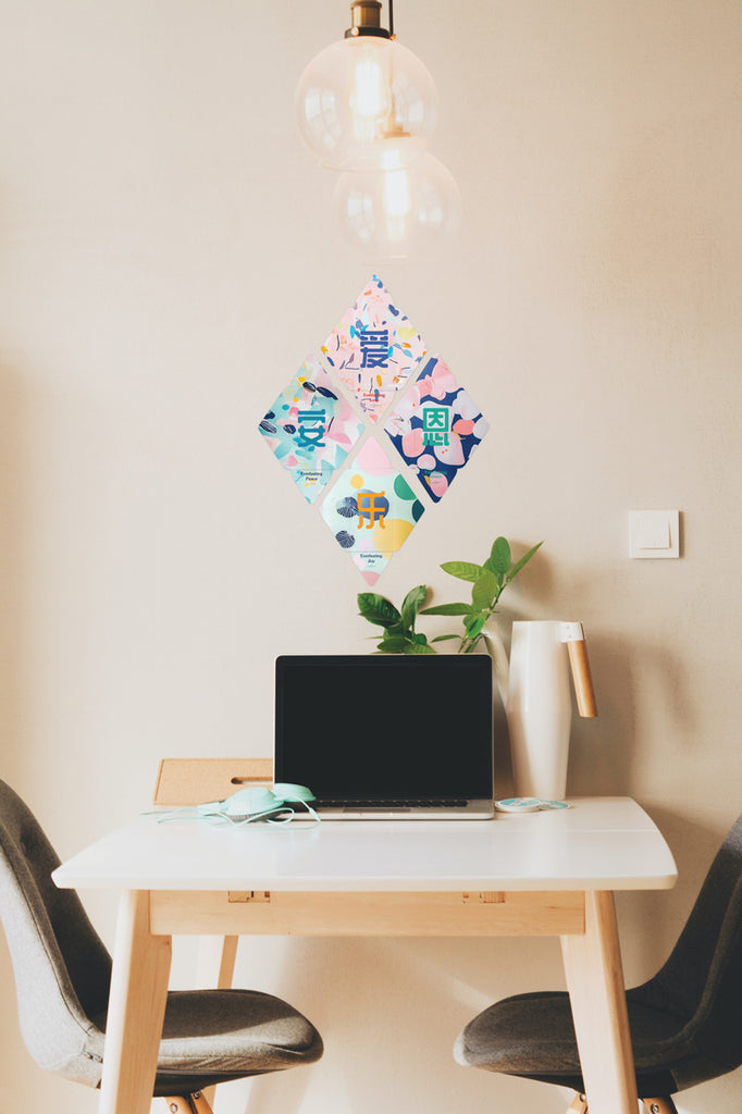 Modern Chinese New Year red packet designs displayed as a diamond-shaped wall decor above a desk setup with a laptop, potted plant, and warm lighting in a cozy workspace.