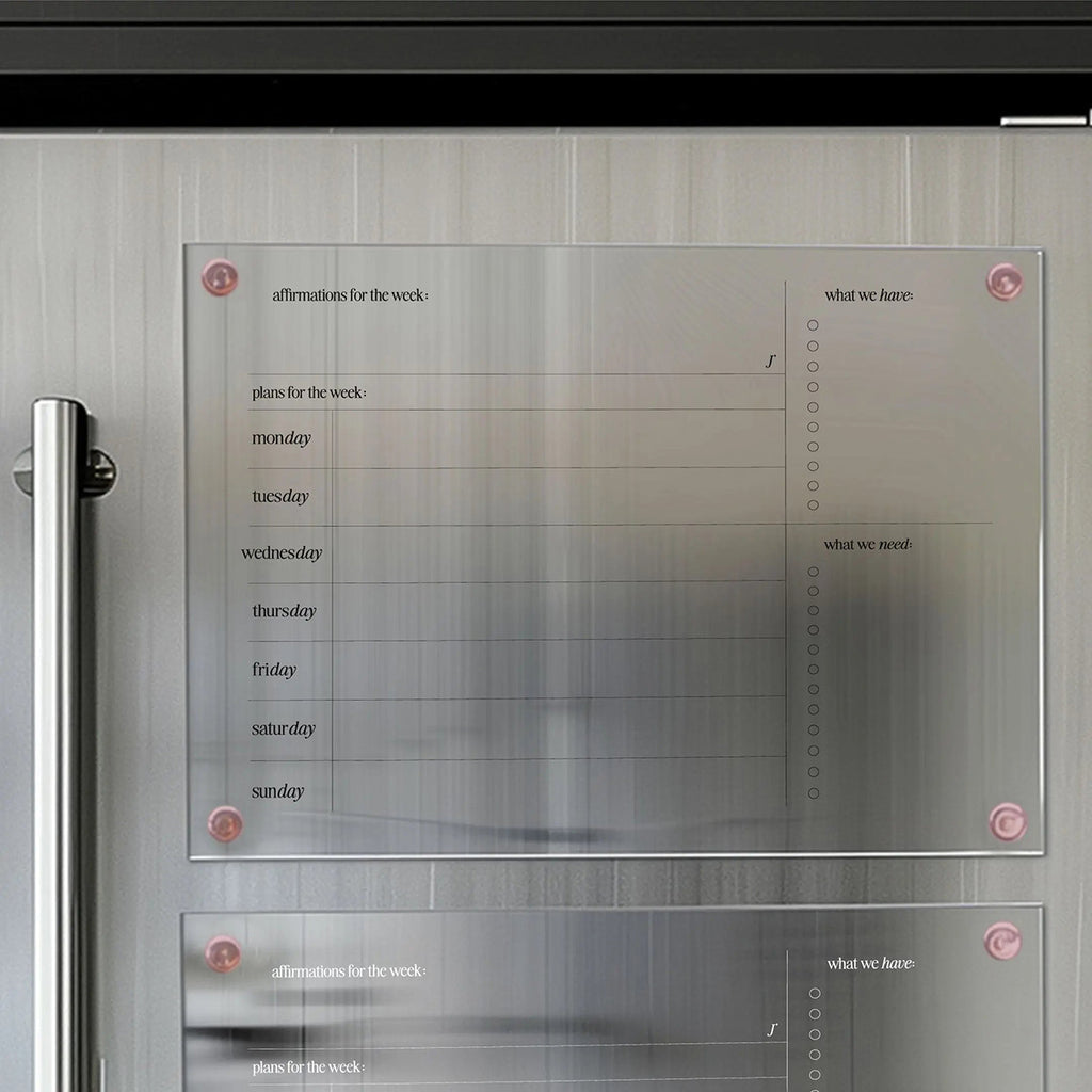 Modern magnetic organizer board for weekly planning, featuring sections for affirmations, daily plans, and checklists for 'what we have' and 'what we need,' mounted on a sleek surface.