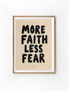 Framed More Faith Less Fear Christian poster with bold black lettering on a warm cream background