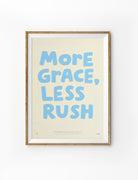 Framed More Grace Less Rush Christian poster with soft blue lettering on a warm cream background