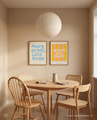 More Grace Less Rush Christian poster displayed with Mustard Seed Energy artwork in a warm neutral dining room