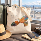 New Strength Isaiah 40:31 canvas tote bag with colourful eagle artwork beside travel essentials at an airport