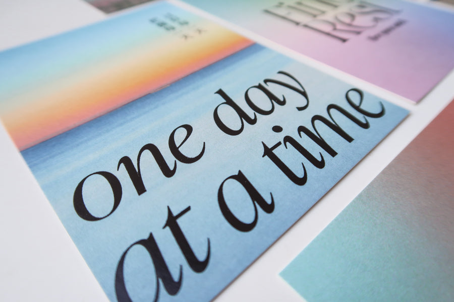 A thoughtfully crafted postcard featuring the uplifting message "One Day at a Time," perfect for spreading positive encouragement and daily motivation.