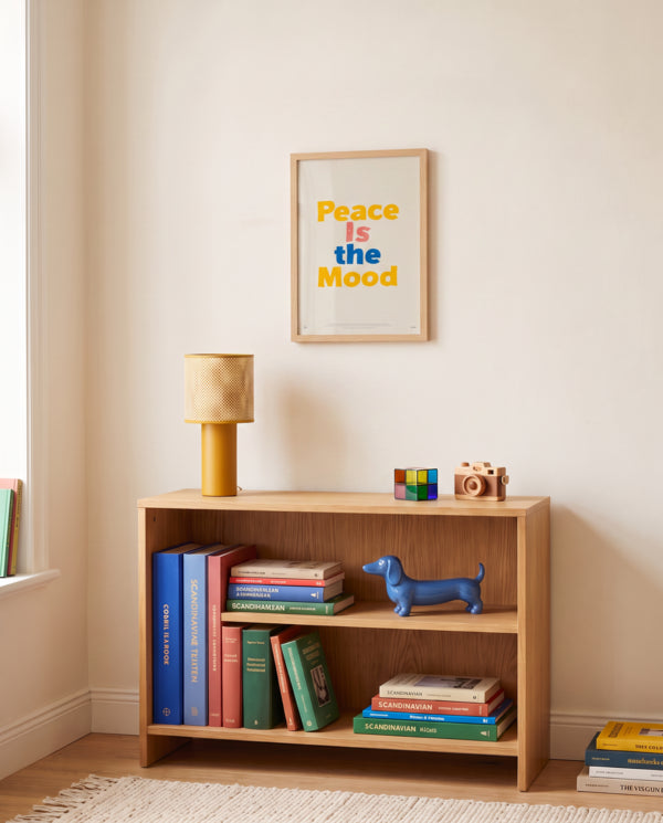 Peace Is the Mood Scripture poster displayed above a wooden bookshelf in a warm neutral room