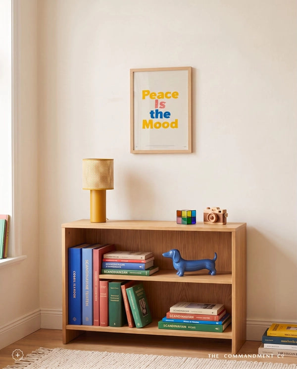 Peace Is the Mood Christian poster displayed above a wooden bookshelf in a warm neutral room