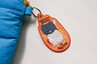 Back view of embroidered faith keychain with “Persevere Boldly in Faith” text and warrior cat illustration in warm orange tones.