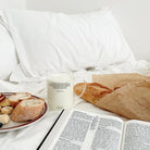 Philippians 4:6 Christian glass cup filled with milk beside an open Bible, bread and breakfast in a peaceful morning setting