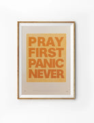 Pray First Panic Never Christian poster with bold orange typography on a warm cream background