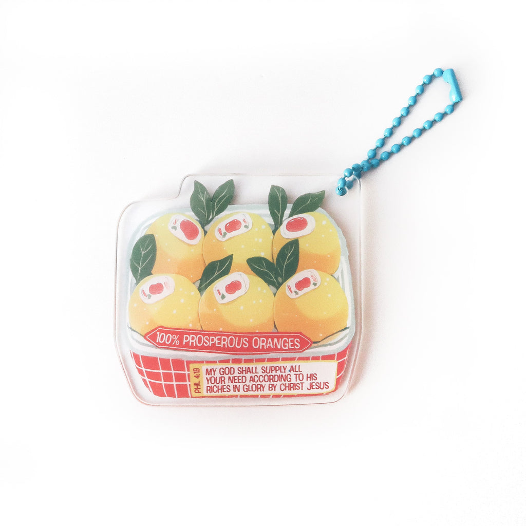 Keychain featuring a basket of oranges with the biblical verse Philippians 4:19: ‘My God shall supply all your needs,’ symbolizing prosperity and faith.