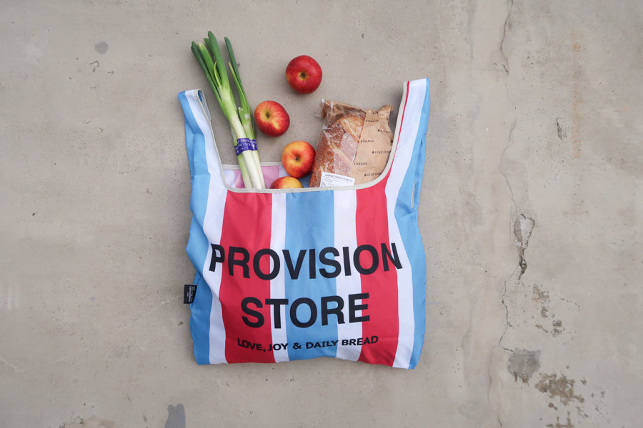 Provision Store foldable 
reusable shopping bag 
with red, blue, and white 
stripes, filled with 
groceries, a thoughtful 
Bible verse shopping bag 
from a Christian gift store.