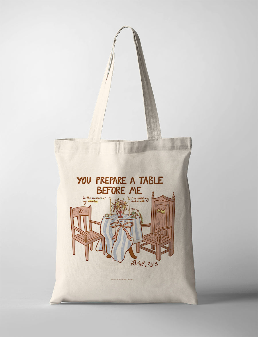 Canvas Christian tote bag featuring Psalm 23:5 illustration of a table with chairs and the phrase “You prepare a table before me” in a warm minimal design