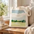 Psalm 23 landscape artwork on canvas tote bag beside cosy cushion on sunlit wooden table