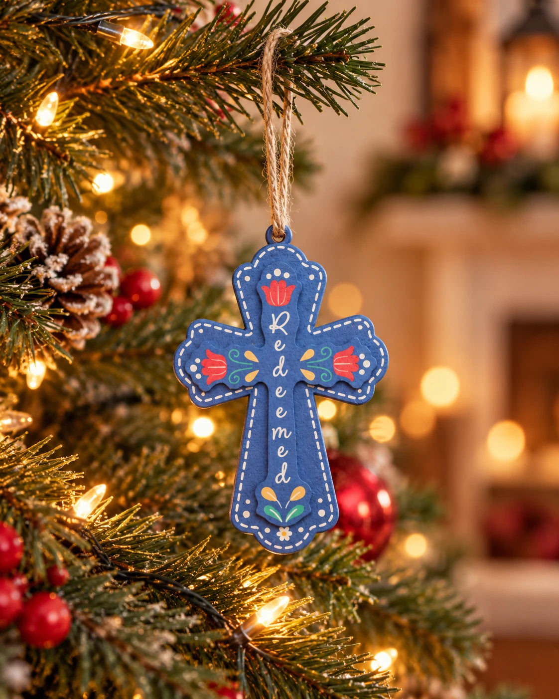 Blue Redeemed cross Christmas tree bauble hanging by string among warm festive lights