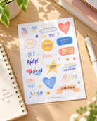 Rejoice Christian journaling sticker sheet with colourful faith phrases displayed on a sunlit desk.