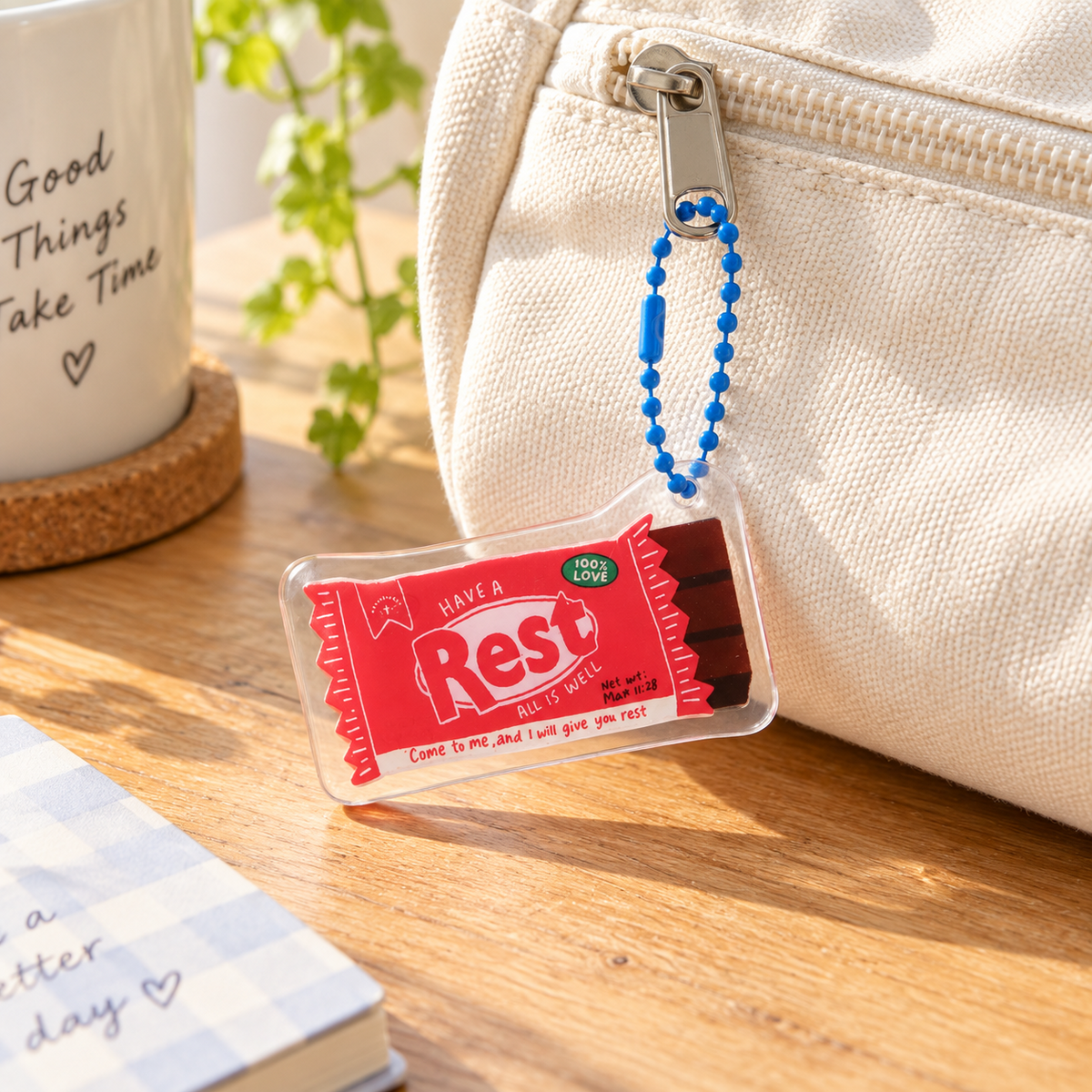 Rest Chocolate Bar acrylic keychain attached to a cream canvas pouch in warm natural light.