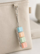 REST light-up keycap keychain clipped to a beige pouch