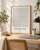Book of Romans framed poster on a bright wooden home office desk