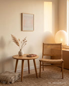Rooted In Love Christian poster displayed in a warm reading corner with a rattan chair, side table and glowing lamp
