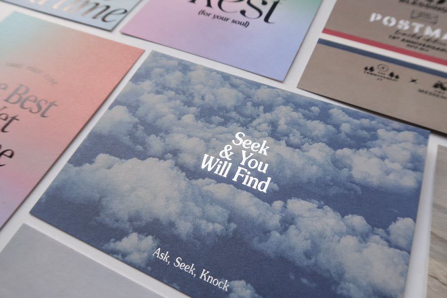 A close-up view of a collection of inspirational postcards, featuring the "Seek & You Will Find" card with a sky and clouds background, alongside other cards with uplifting messages.