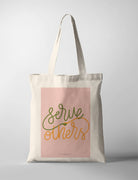 Christian tote bag featuring “Serve others” with hand-lettered text and a small handshake illustration