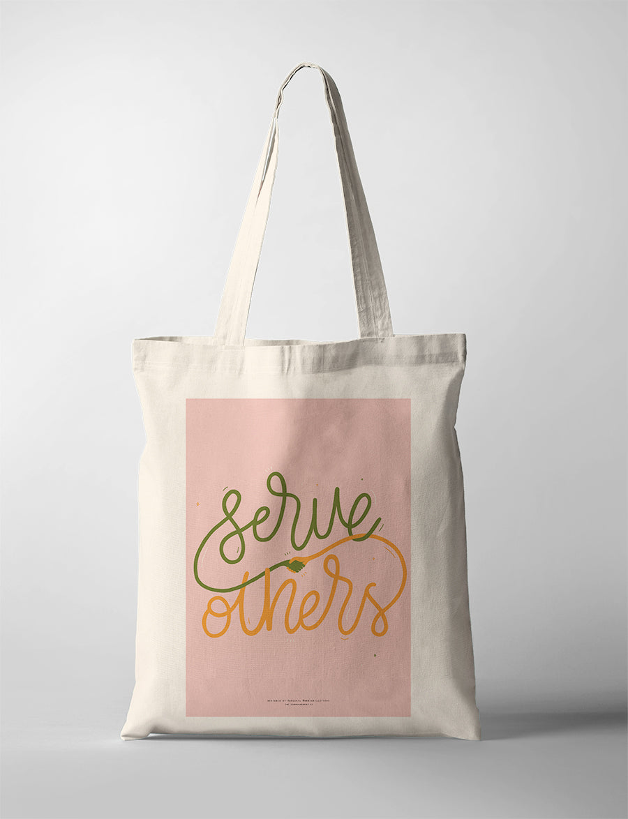 Christian tote bag featuring “Serve others” with hand-lettered text and a small handshake illustration