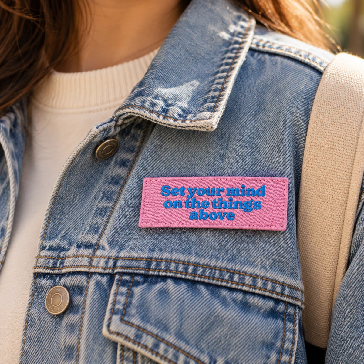 Pink Set Your Mind on the Things Above embroidered Velcro tag attached to a denim jacket