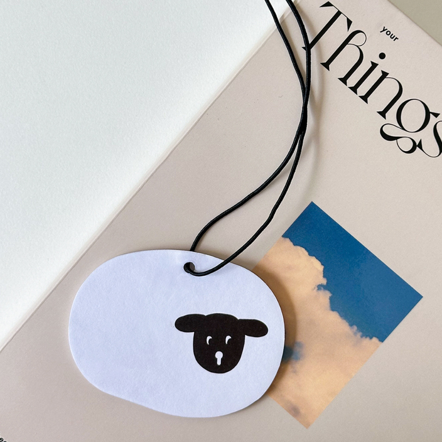Sheep scent tag featuring a simple black sheep illustration, symbolizing comfort and encouragement, placed on a book for a touch of simple happiness.