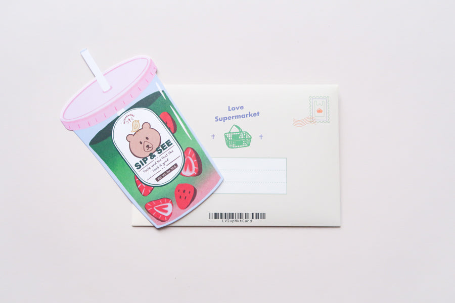 Sip & See matcha drink–shaped Christian postcard displayed with its Love Supermarket envelope.