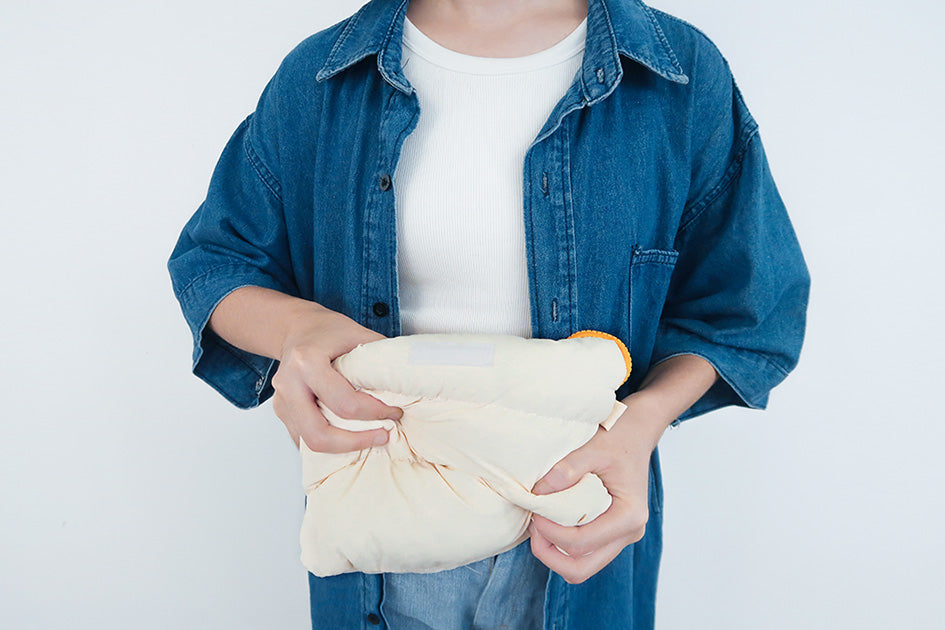 Close-up of the Oat Pong Pong Bag being squeezed to show its soft, cushioned texture.