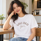 Lifestyle photograph of a woman wearing the white Soli Deo Gloria T-shirt in a cosy interior.