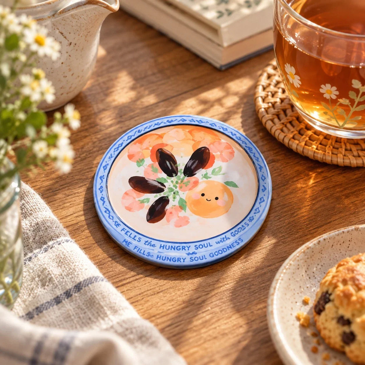Soul Satisfying Congee Christian coaster on a wooden tabletop beside a glass of tea and flowers.