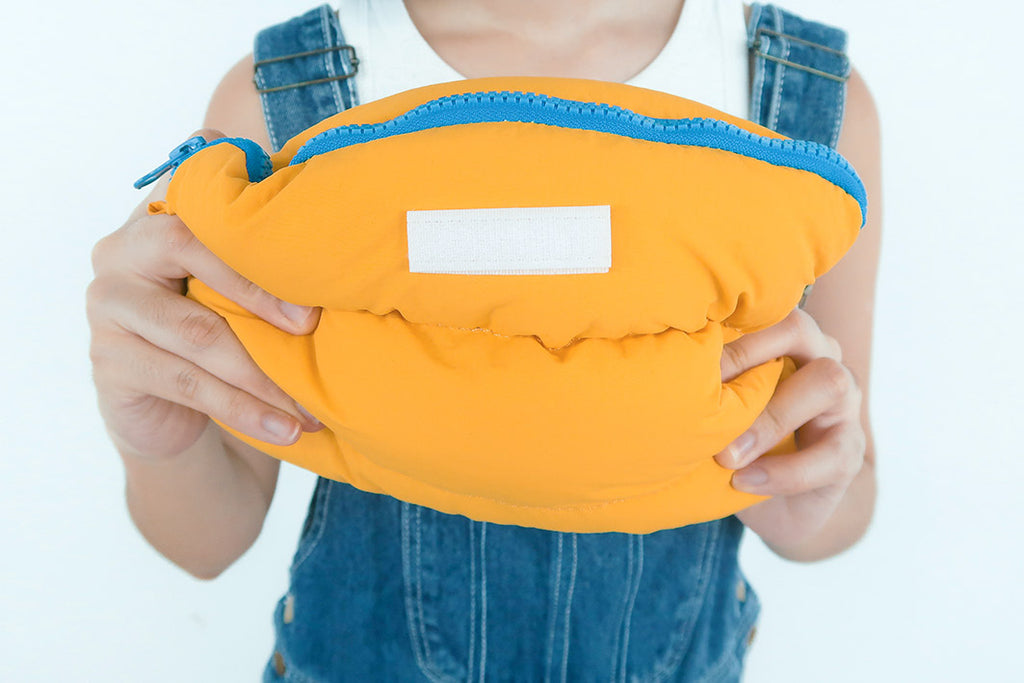 Yellow Pong Pong Bag being compressed, demonstrating its fluffy and flexible nature for convenient storage.