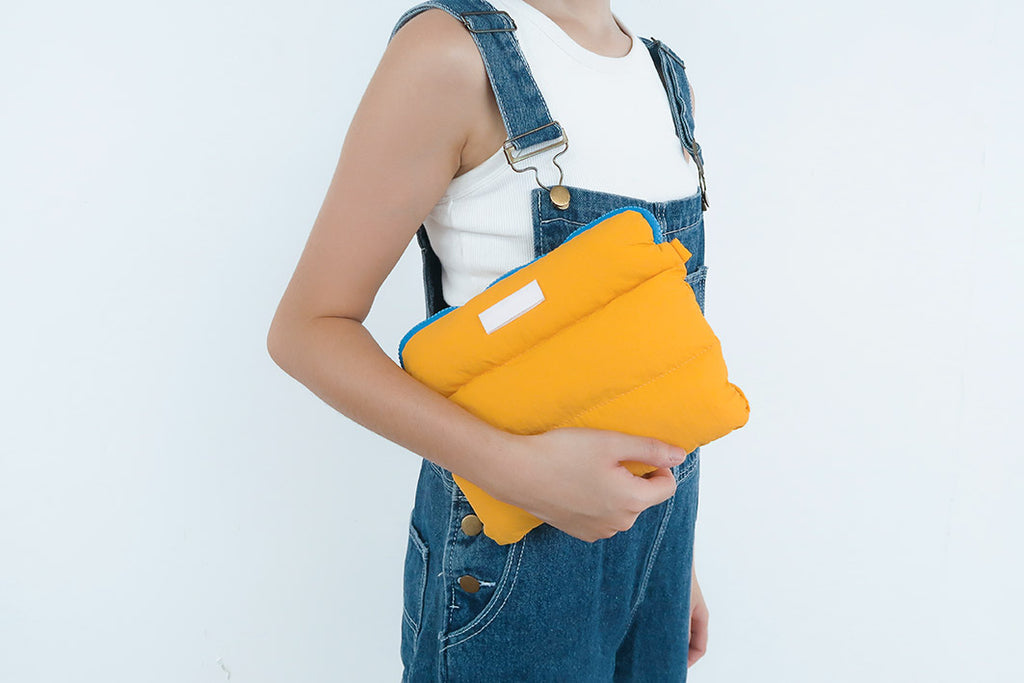 Person holding the Yellow Pong Pong Bag, emphasizing its soft, fluffy texture and multipurpose storage capabilities.