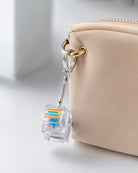 Super Blessed light-up keycap keychain clipped to a beige bag