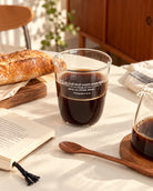 Supply All Your Needs Philippians 4:19 clear glass cup filled with coffee beside bread and a book on a sunlit table