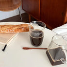 Philippians 4:19 Bible verse glass cup filled with coffee beside a glass pitcher, bread and book