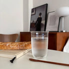 Clear Christian glass cup featuring Philippians 4:19 filled with water on a table beside bread and a book